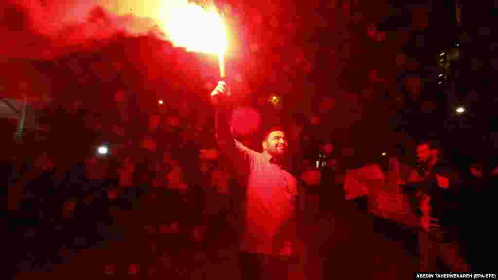 Egy iráni férfi fáklyával ünnepel Teheránban. A szombati akció az első közvetlen támadás izraeli terület ellen, ami komoly eszkalációval fenyeget