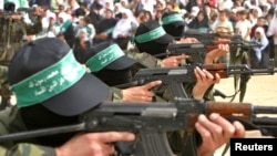 Membrii grupării militante Hamas mărșăluiesc cu puști AK 47 în timpul unui miting în tabăra Bureij din Fâșia Gaza, pe 5 martie 2004.