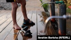 Një fëmijë afgan teksa pastron këmbët nga rëra e plazhit në Shëngjin.