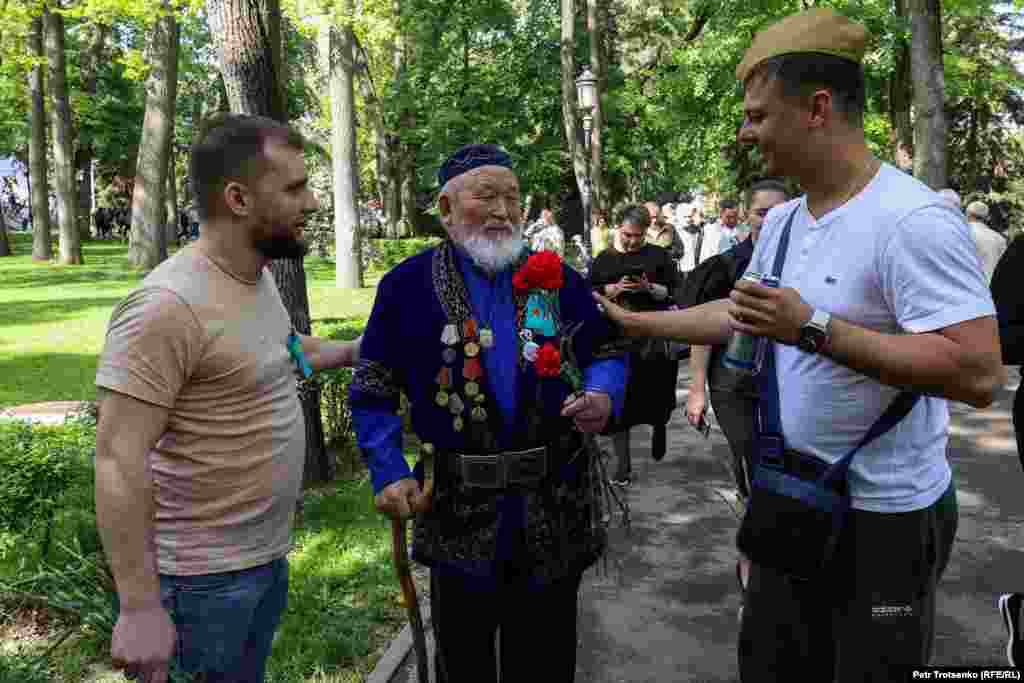 Мужчины поздравляют пожилого человека с Днём Победы