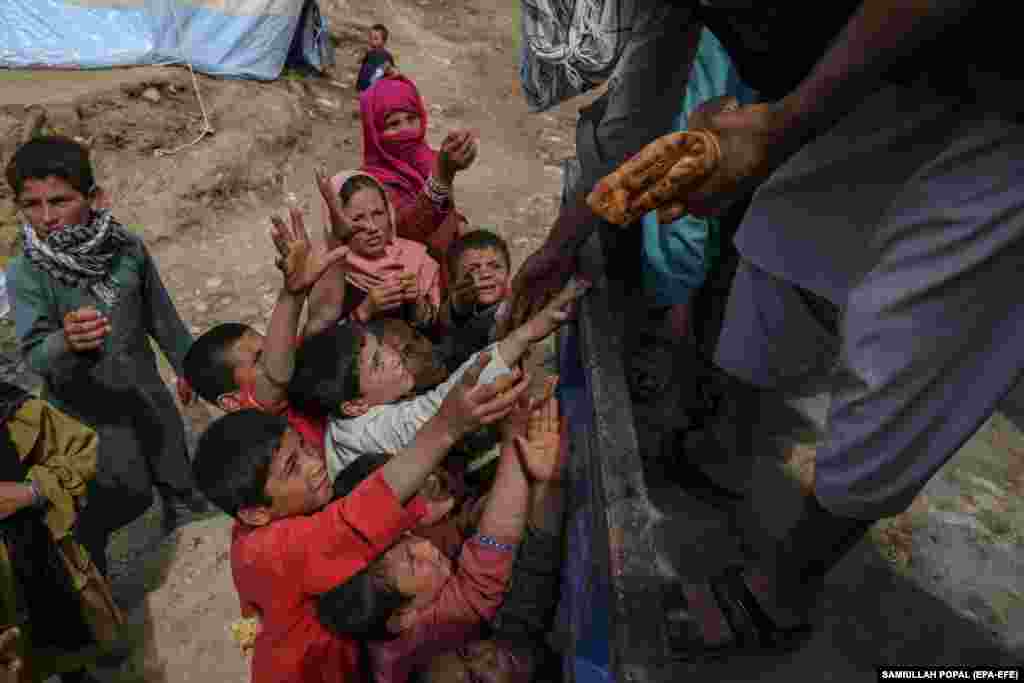 Vullnetarët duke u shpërndarë bukë njerëzve të prekur nga vërshimet në fshatin Shiralal.