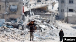 Palestinci prolaze pored kuća koje su uništene u izraelskom napadu, Kan Junis, jug Pojasa Gaze, 22. maja 2024.