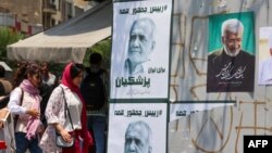 A kötelező fejkendőviseletet semmibe vevő fiatal nők sétálnak el a mérsékelt Pezeskian és a keményvonalas Dzsalili választási plakátjai előtt Teheránban