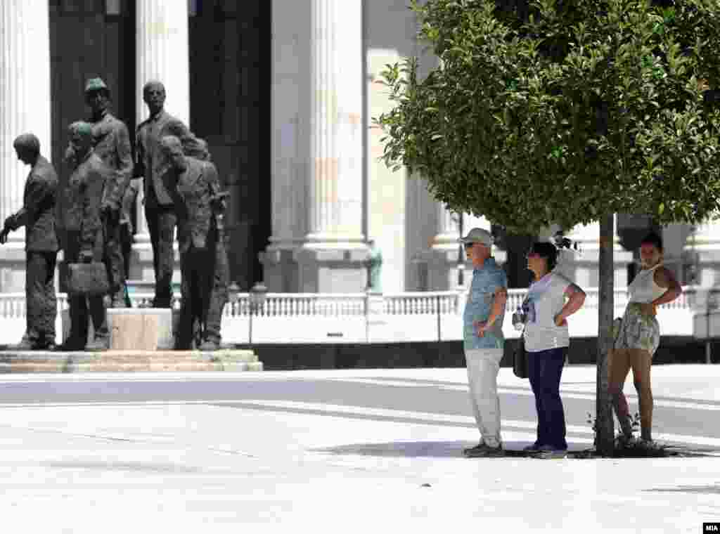 Ljudi u Skoplju stoje u hladu ispod drveta, 9. jul 2024.