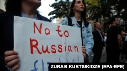 O femeie protestează în fața Parlamentului de la Tbilisi împotriva reluării zborurilor directe între Rusia și Georgia, Tbilisi, 16 mai 2023. 