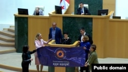 დეპუტატმა ქალებმა კულტურის მინისტრის გამოსვლისას გაშალეს ბანერი უკრაინელი სამხედროს ცნობილი ფრაზით.