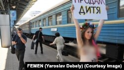Jedna od fotografija sa protesta feminističke i antiratne grupe FEMEN protiv surogat majčinstva u Ukrajini, u Kijevu, maj 2011. Na transparentu piše "Prodajem bebu".