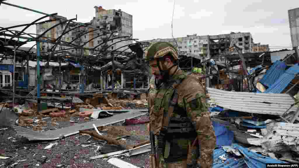 Украински войник минава край руини в Бахмут, 23 април 2023 г.