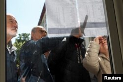 Disa qytetarë kontrollojnë listën e votuesve gjatë zgjedhjeve presidenciale, në Shkup, Maqedonia e Veriut, 24 prill 2024.