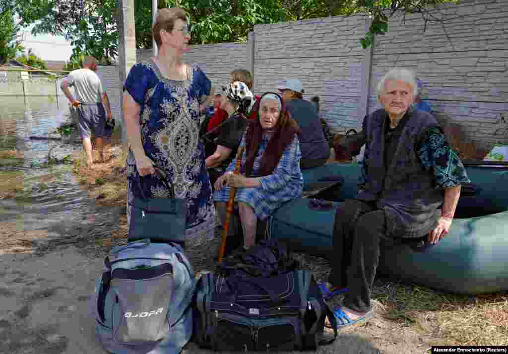 Ljudi sede na čamcima na naduvavanje nakon evakuacije iz Hola Pristana.