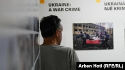 Posetilac gleda u jednu od izloženih fotografija. Na njoj se vidi Irina Kalinina kako je evakuisana na nosilima iz porodilišta koje je napala Rusija u martu 2022. Ona i njena beba nisu preživele napad.