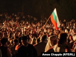 Egy férfi bolgár zászlót tart az augusztus 19-i máglyagyújtás előtt