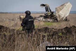 Un genist al Serviciului de stat pentru situații de urgență al Ucrainei lucrează la deminarea unui teren în apropiere de Izium, regiunea Harkov.