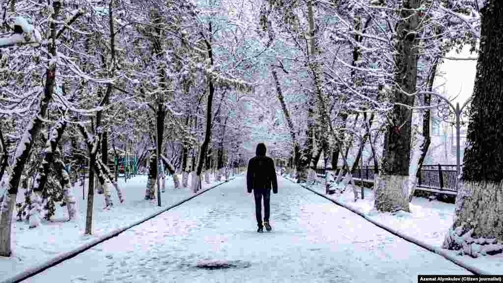 Čovjek hoda snijegom prekrivenom stazom u Ošu, Kirgistan.