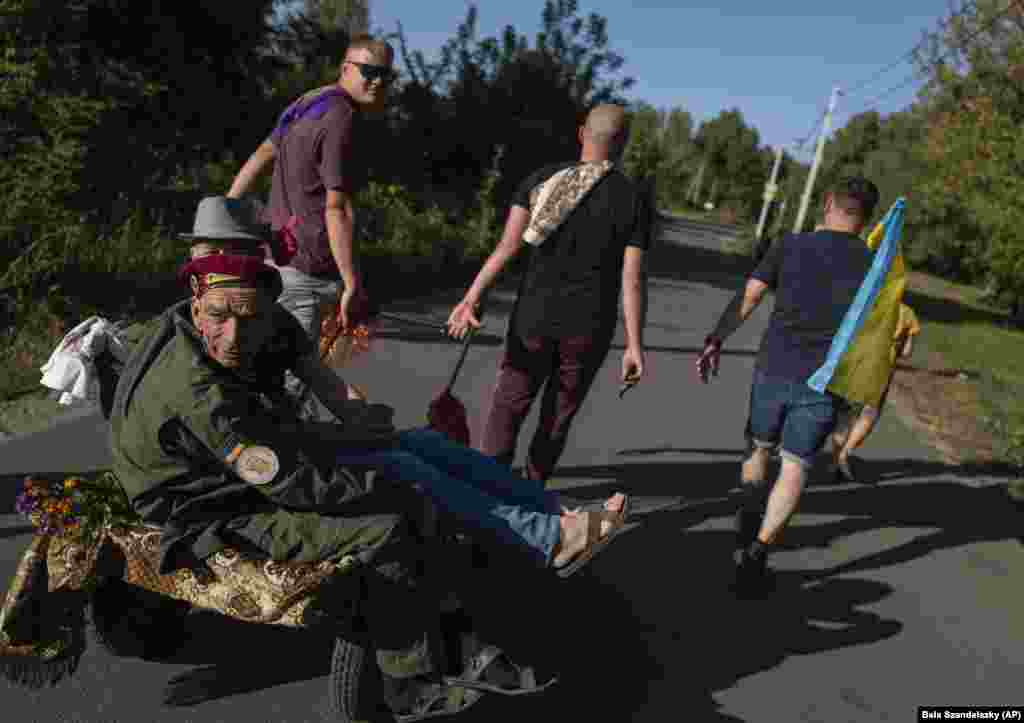 Oleksandr Soroka, 55 vjeç, tërhiqet në një karrocë dore nga familjarët dhe mysafirët gjatë festës së dasmës, ku më vonë u hodh në ujë për ta festuar largimin e të birit nga shtëpia. Veterani i ushtrisë sovjetike tha më vonë se ai ka mundur të regjistrohej në ushtri në vend të të birit. &ldquo;E fajësoj veten&rdquo;, tha ai duke iu dridhur zëri.