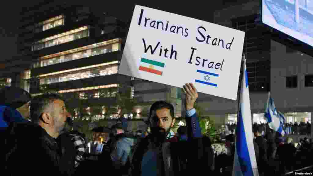 Egy férfi &bdquo;Az irániak kiállnak Izrael mellett&rdquo; feliratú táblát tart egy Izraelt támogató gyűlésen a kanadai Torontóban október 9-én