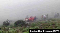Ova fotografija preuzeta iz video snimka koji je objavio iranski Crveni polumjesec 20. maja 2024. prikazuje spasioce koji izvlače tijela na mjestu pada helikoptera predsjednika Ebrahima Raisija u maglom prekrivenom planinskom području sjeverozapadnog Irana. 