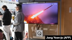 Dy burra shihen afër një ekrani që transmeton testimet raketore të verikoreanëve. Fotografi nga arkivi.