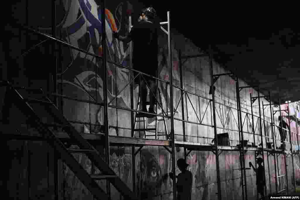 Artiștii maghiari NEMK, 210 și Bronk pictează pe peretele unui tunel feroviar.