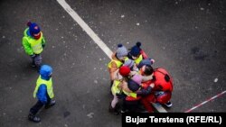 Djeca okupljena ispred Pedijatrijske klinike u Prištini grle djevojku obučenu u kostim superheroja, decembar 2023.