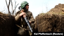 Un soldat ucrainean cercetează pozițiile inamice din tranșee, estul Ucrainei. (fotografie de arhivă)