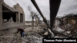 Žena raščišćava ruševine u dvorištu kuće koja je uništena u ruskom raketnom napadu, u Selidovu kod Avdijevke, Ukrajina, 19. februara 2024.