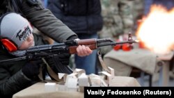 An officer of Belarus's Interior Ministry teaches a child to fire an automatic weapons in March 2020