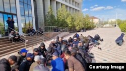 Рабочие, требующие трудоустройства, сидят перед офисом предприятия «Озенмунайгаз». Жанаозен, 4 апреля 2023 года