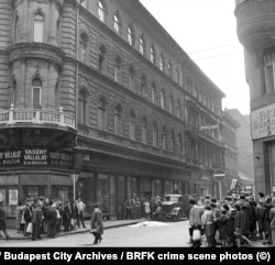 Kíváncsiskodók gyűlnek egy letakart holttest köré Budapesten