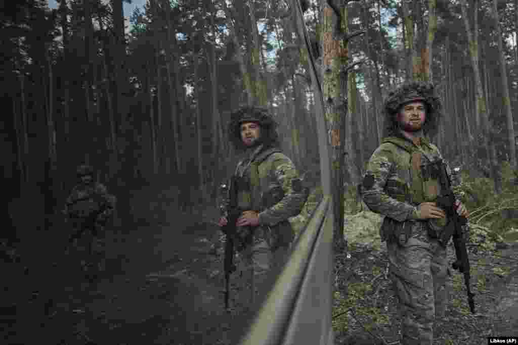 A Ukrainian policeman is reflected in a window as the unit prepares to fire toward Russian positions near Kreminna.