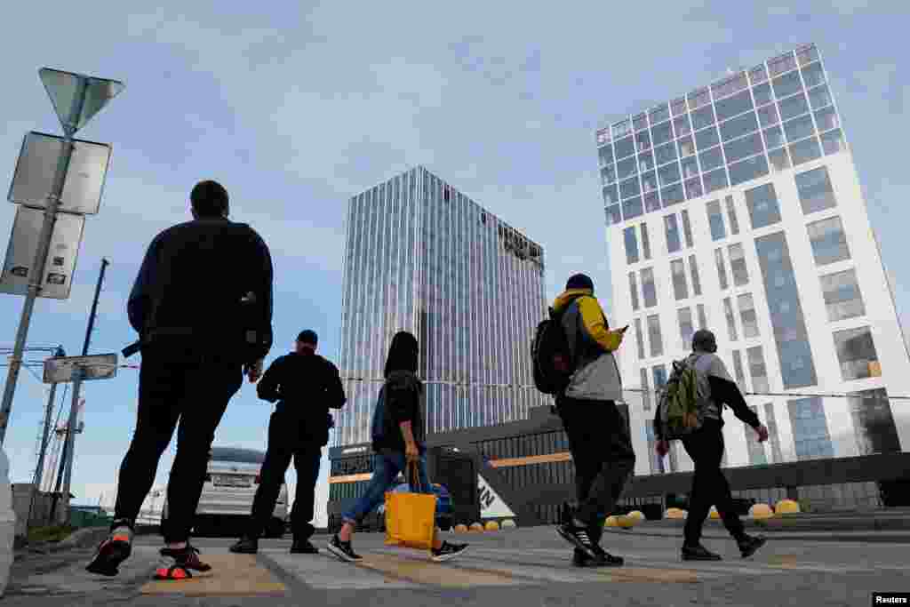 Луѓе поминуваат покрај оштетената зграда во Москва.