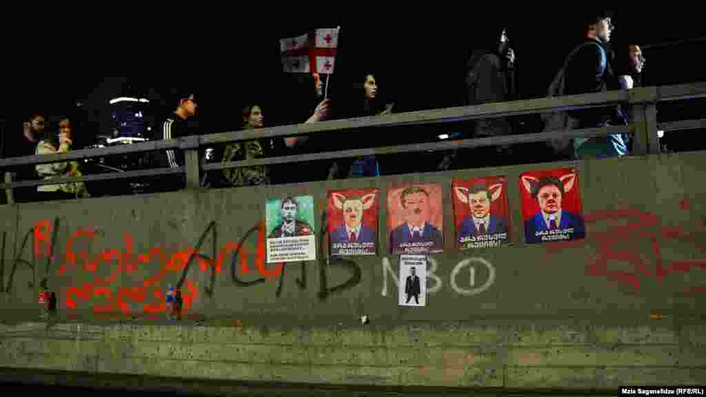 A kormányzó Grúz Álom párt vezetőinek portréi &bdquo;Nem az orosz rezsimre&rdquo; felirattal. A javasolt jogszabály ellenzői úgy vélik, hogy a szólásszabadság és a független média rovására menne.&nbsp;A hasonló oroszországi jogszabályok miatt orosz törvénynek is gúnyolják