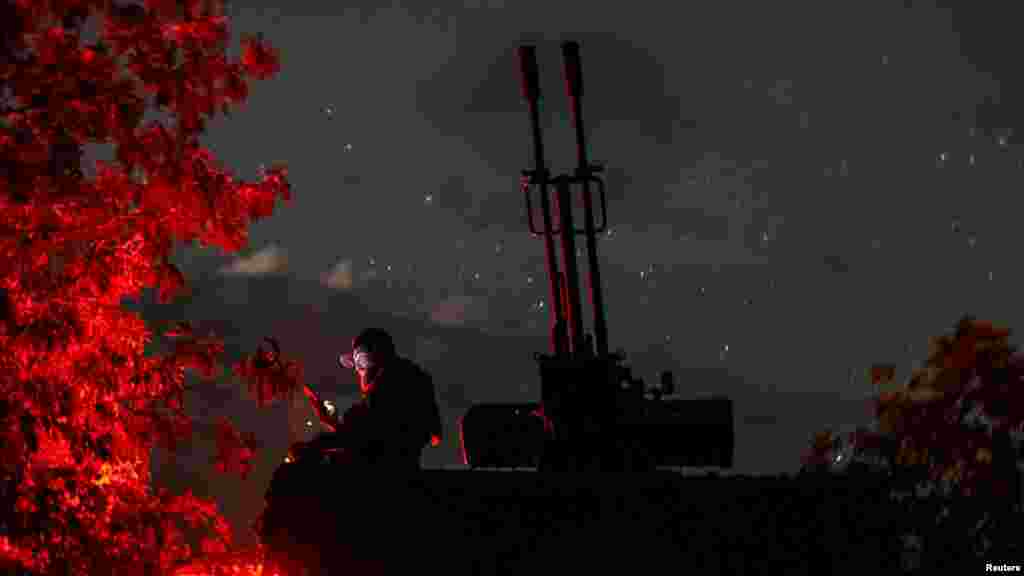 Një ushtar ukrainas nga një njësi lëvizëse e mbrojtjes ajrore anti-dron përdor telefonin e tij pranë një topi kundër avionit ZU-23-2 ndërsa pret dronët kamikazë rusë, në rajonin e Hersonit, Ukrainë, 11 qershor.