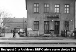 Az előző képen látható rendőr egy másik egyenruhás férfira szegezi a pisztolyát, aki egy Kalasnyikovot tart a kezében. A felvétel a hetvenes években, egy bűnügyi helyszínelésen készült