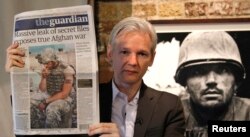 Julian Assange arată ediția din 26 iulie 2010 a ziarului The Guardian în timpul unei conferințe de presă la Frontline Club din centrul Londrei.