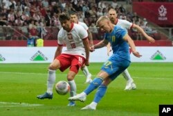 Ukrajinac Oleksandr Zinčenko šutira loptu ispred Poljaka Bartoša Berešinskog tokom međunarodne prijateljske fudbalske utakmice između Poljske i Ukrajine na Nacionalnom stadionu u Varšavi, Poljska, 7. jun 2024.