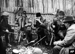 Sedeći oko logorske vatre, predsednik Tito Jugoslavije i članovi jugoslovenskog diplomatskog kora uživaju u ručku za piknik u šumi u Karađorđevu u blizini mađarske granice, Jugoslavija, negde krajem decembra 1957, prže meso na vatri. Ovu sliku napravio je Titov sopstveni fotograf u jednoj lovačkoj ekspediciji u Karađorđevu. S leva na desno su: jugoslovenski ministar inostranih poslova Koča Popović; Žorž Delkojn, belgijski ambasador u Jugoslaviji; Džejms Ridlberger, ambasador Sjedinjenih Država; Tito i Ribeiro Couto, brazilski ambasador i dekan diplomatskog kora.