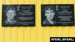 Plăci comemorative pe școala din satul Kuratovo, unde au studiat Semion (stânga) și Aleksandr Tutrinov.