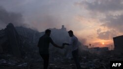 Palestinezët duke kërkuar për gjëra që kanë shpëtuar në rrënojat e një ndërtese të shkatërruar nga sulmet ajrore izraelite në qytetin e Gazës, më 8 tetor 2023.