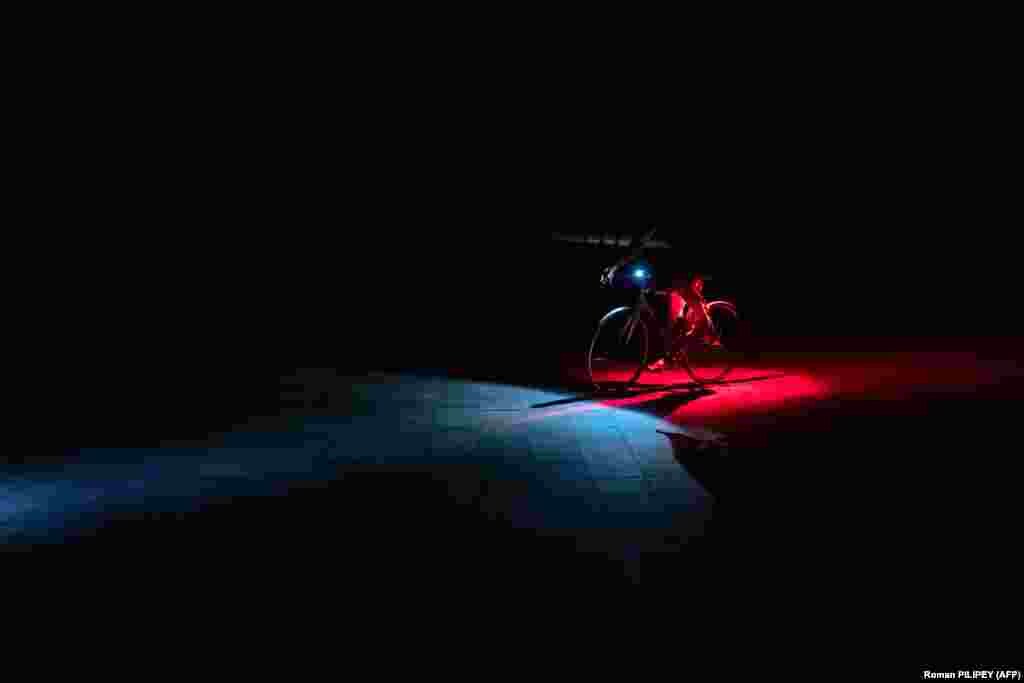 Biciklista vozi zamračenom ulicom tokom delimičnog nestanka struje u Kijevu.