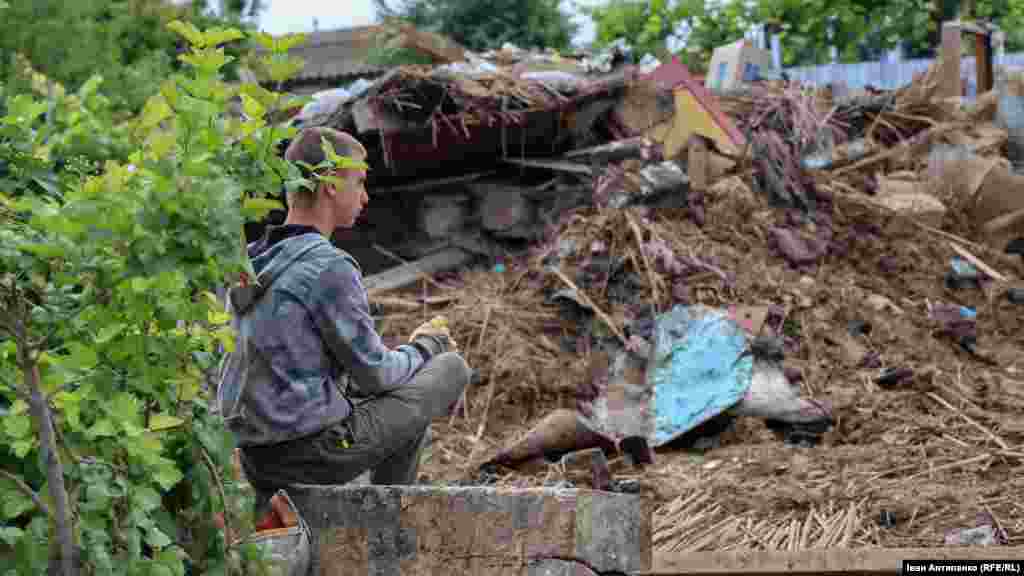 Evhen, 13 ani, se uită la noroiul și molozul care acoperă locul unde a fost casa lui în satul Bilozerka, regiunea Herson din sudul Ucrainei, pe 14 iunie. Mii de case au fost afectate de ruperea barajului Kahovka din 6 iunie. Comunitățile din aval, de-a lungul bazinului fluviului Nipru, au fost acoperite de apă, producându-se cel mai mare dezastru ecologic al invaziei Rusiei în Ucraina.