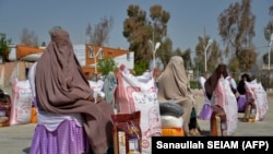 Gratë afgane ulen pasi kanë marrë ndihma ushqimore të shpërndara nga një fondacion bamirësie gjatë muajit të shenjtë mysliman, Ramazanit, në Kandahar (Fotografi nga arkivi).