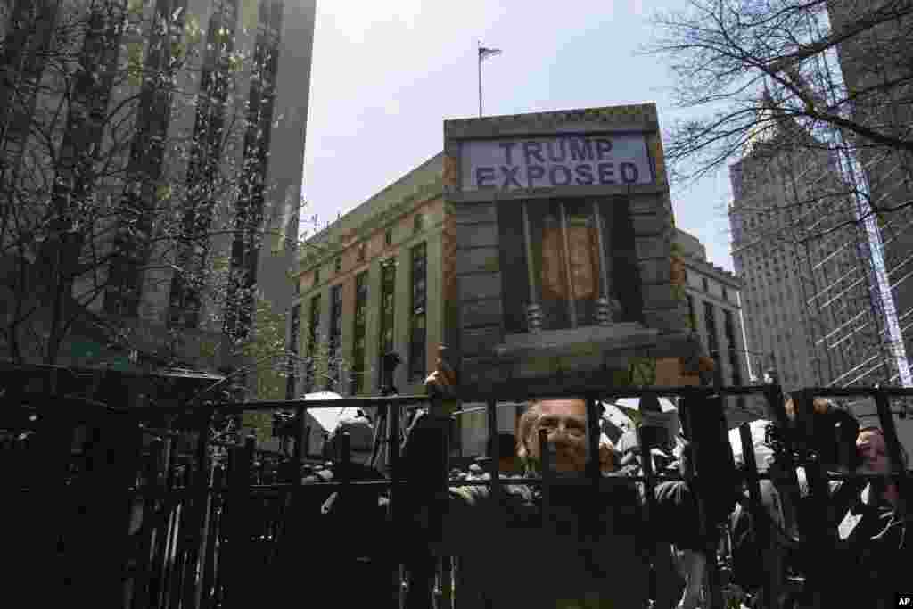 Osoba drži znak na kojem piše &#39;Trump razotkriven&#39; na protestu u Collect Pond Parku prekoputa ureda okružnog tužioca Manhattana u New Yorku u utorak, 4. aprila 2023.