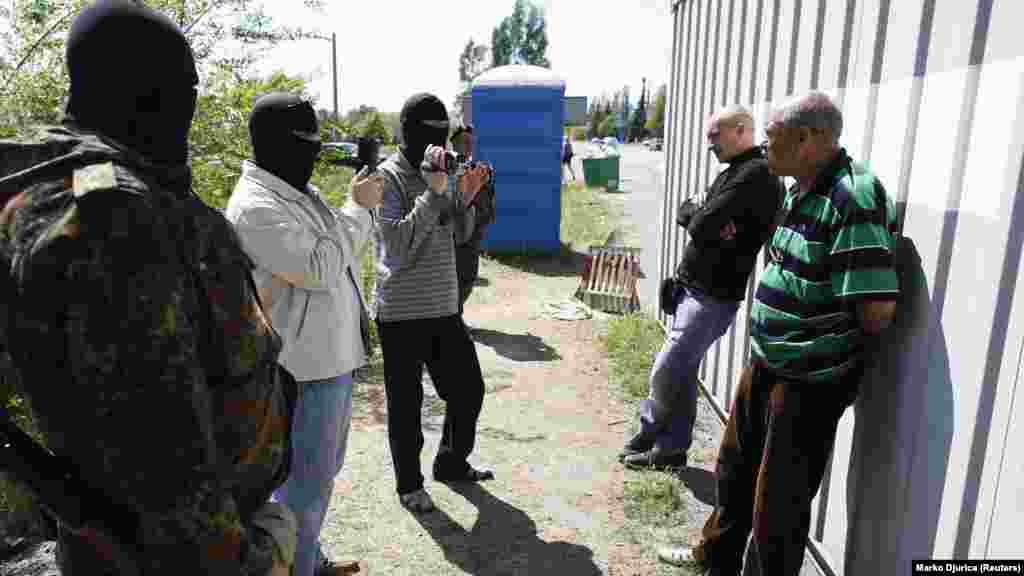 Maszkos ukrán rendőrök két férfit hallgatnak ki egy Mariupol melletti ellenőrző ponton 2014. május 11-én. Az ukrán csapatok ellenőrző pontokat állítottak fel Mariupol körül, mivel a helyzet a központban továbbra is feszült maradt