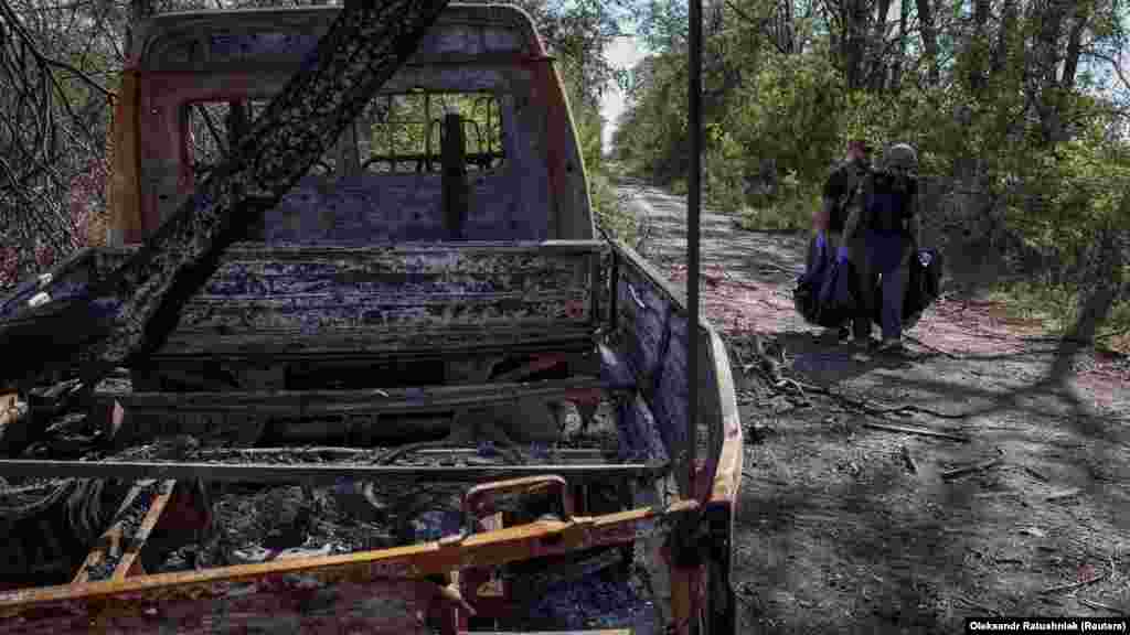 Volodimir, egy ötvenéves tengerészgyalogos (jobbra) és egy kollégája egy orosz katona holttestét viszi egy kiégett teherautó mellett. &bdquo;A szemünkkel és az orrunkkal kutatunk a halottak után&rdquo; &ndash; mesélte. Hogy megbizonyosodjanak arról, hogy a holttesteket &ndash; pontosabban, ahogy arra már volt példa, a honfitársaik holtteste alá helyezett aknákat &ndash; nem a kivonuló orosz csapatok rejtették el, a katonák gyakran mérőeszközzel szondázzák, bottal forgatják át a testeket