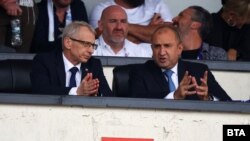 Премиерът Николай Денков и президентът Румен Радев разговарят на трибуните на националния стадион "Васил Левски" по време на "Мач на надеждата", организиран от футболиста Стилиян Петров на 6 септември 2023 г.