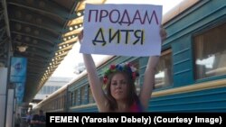 Držeći transparent "Prodajem bebu" aktivistkinja antiratne grupe FEMEN protestuje protiv surogat majčinstva u Ukrajini, Kijem, u maju 2011.