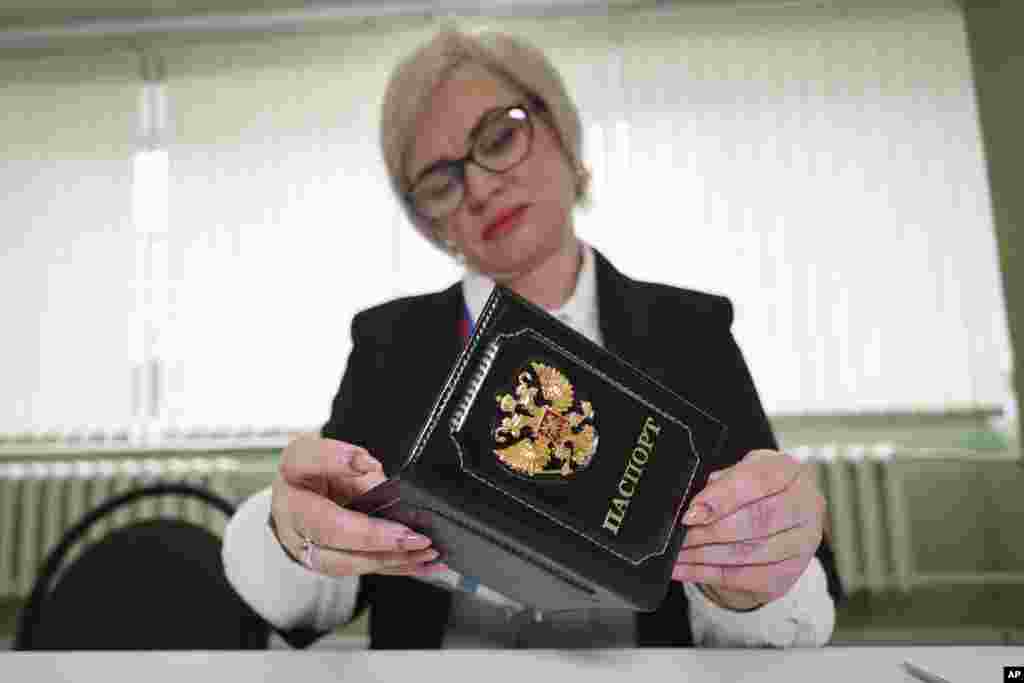 Članica izborne komsije u gradu Makivka u ukrajinskom regionmu Donjeck pod okupacijom Rusije. Centralna izborna komisija je navela da će izbore posmatrati &quot;od 500 do 1.000 međunarodnih posmatrača iz više od 100 država i od 13 do 15 međunarodnih organizacija&quot;. Posmatrači, međutim, nisu pozvani iz država sa spiska &quot;neprijateljskih&quot;, među kojima su sve članice Evropske unije, SAD i Velika Britanija kao ni iz OEBS-ove Kancelarije za demokratske institucije i ljudska prava (ODIHR) koja inače posmatra izbore.