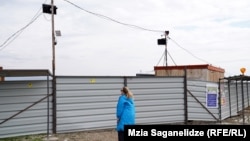 ბეტონის ქარხნის სამშენებლო მოედნის ჭიშკარზე დამონტაჟებული ვიდეოკამერები ღობესთან მიახლოებულ ადამიანებს აფრთხილებენ "დატოვონ კერძო ტერიტორია".