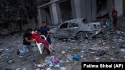 Palestinezë duke ecur mes rrënojave, pas sulmeve ajrore izraelite, që rrafshuan pjesë të mëdha të një lagjeje në Qytetin e Gazës, më 10 tetor 2023.